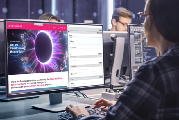 Eine Person arbeitet an einem Computer, auf dem die Website von Brainlab zu sehen ist, die mit einem Kirby Headless CMS Ansatz entwickelt wurde.